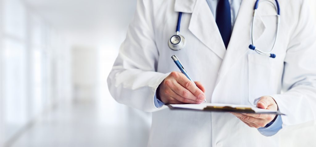 Male doctor writes notes on the clipboard in the hospital